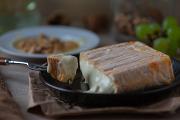 French soft cheese with mold from Alsace on a marble stone with walnut, honey, grapes and white wine