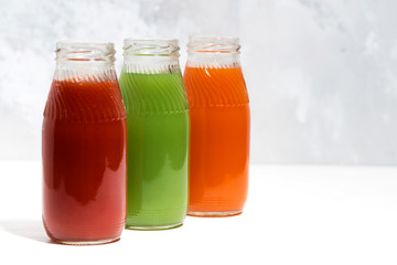 colorful vegetable juices in bottles on white table