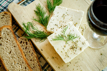 white cream cheese with herbs and spices on a wooden Board decorated with fresh dill, slices of bread and ripe tomatoes