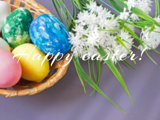 Easter eggs in a basket on a gray background and blooming white flowers