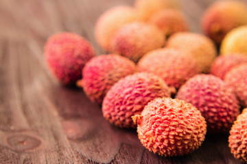Fresh organic lychee fruit on brown wooden background.