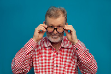 Happy positive man pensioner wearing red shirt and stylish eyeglasses