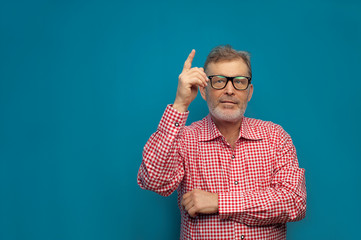 Naklejka premium Handsome elderly man wearing smart casual style and eyeglasses showing something useful