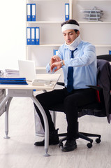 Young injured male employee working in the office 
