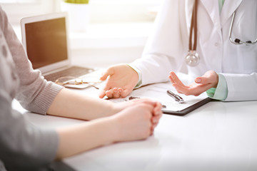 Doctor and  female patient sitting at the desk and talking  in clinic near window. Medicine and health care concept. Green is main color