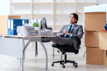 Young man employee with boxes in the office 