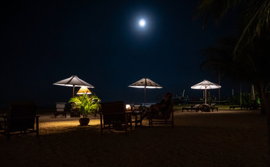 Lighted outdoor restaurant in Bali with full moon on dark sky