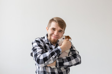 people, pets and animals concept - close up of young man holding jack russell terrier puppy on white background