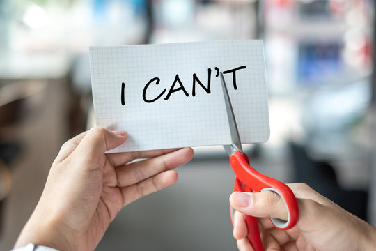 Business man hand holding red scissors and cutting white paper with the text I CAN'T change word to I CAN. challenge, positive thinking and success concept