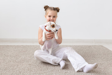 Dogs, children and pets concept - little child girl sitting on the floor with cute puppy