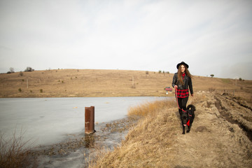 A young girl walks with a dog on the shore of a lake