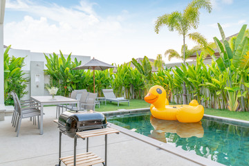 home or house Exterior design showing tropical pool villa with greenery garden, sun bed and floating duck