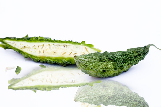 Raw organic bitter melon or Bitter Cucumber or Bitter Gourd isolated on white with its reflection.