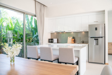 Luxury interior design in living room of pool villas. Airy and bright space with high raised ceiling with open kitchen