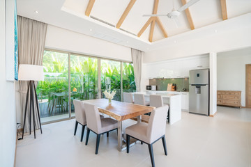Luxury interior design in living room of pool villas. Airy and bright space with high raised ceiling with open kitchen
