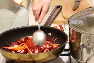 Frying red beets and carrots for cooking borscht