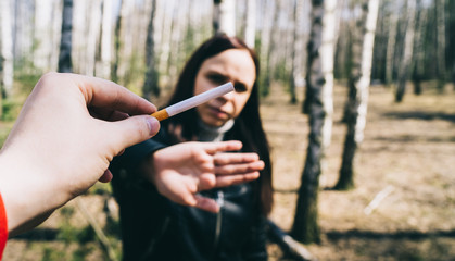 Woman refusing to take cigarette. Crop male hand offering cigarette to woman meeting stop gesture...