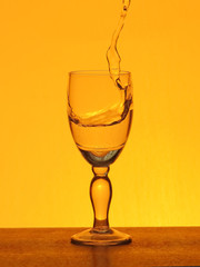 Spray liquid (clear water, red wine) from a glass goblet.