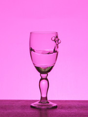 Spray liquid (clear water, red wine) from a glass goblet.