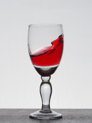 Spray liquid (clear water, red wine) from a glass goblet.