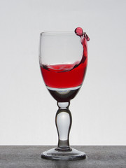 Spray liquid (clear water, red wine) from a glass goblet.