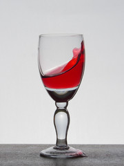 Spray liquid (clear water, red wine) from a glass goblet.
