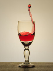 Spray liquid (clear water, red wine) from a glass goblet.