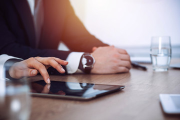 Fototapeta premium Group of business people or lawyers work together at meeting in office, hands using tablet and making notes close-up. Negotiation and communication concept