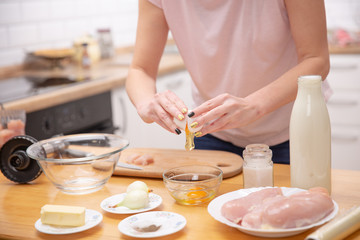 Closeup of a pair of hands cracking an egg into a glass bowl
