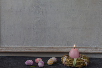 Easter composition on dark stone table and white vintage wall in background