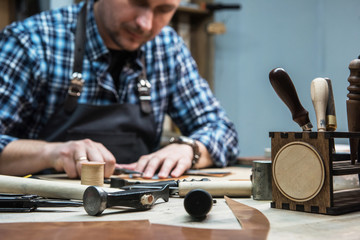 Man making leather wallet at a workshop. Concept of handmade craft production of leather goods.
