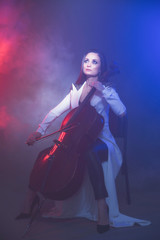 Beautiful woman in a white coat plays the cello