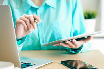 Business woman looking and studying statistics on tablet display closeup. Female left hand holds pen, right holds tablet.