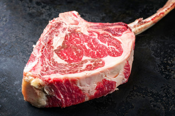 Rohes dry aged Wagyu Tomahawk Rinder Steak als closeup auf einem alten rustikalen Board 