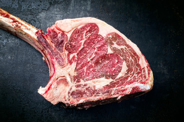 Raw dry aged wagyu tomahawk steak as top view on an old rustic board