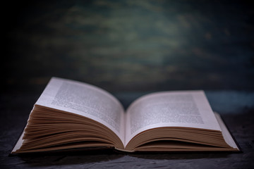 Open book on a stack of books on a table on a dark background. Education and reading of paper books
