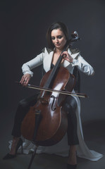 Beautiful woman in a white coat plays the cello