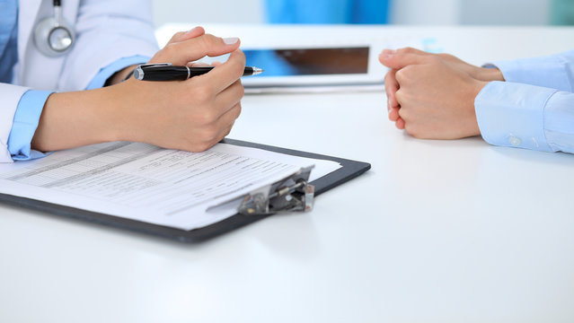 Doctor and patient discussing something, just hands at the table, white background