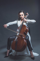 Beautiful woman in a white coat plays the cello