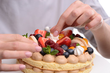 Obraz na płótnie Canvas Girl cook a cake decorated with berries, strawberries, raspberries and mint