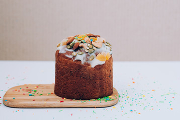 Selective focus close up image of freshly baked delicious Easter cake freshly baked, multicolored sweet sprinkles, on wooden board. Easter, birthday greeting card or web banner concept