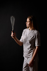 baker girl with a whisk on black background