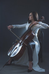Obraz na płótnie Canvas Beautiful woman in a white coat plays the cello