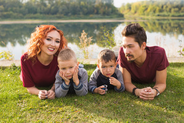 Fototapeta premium Children, parenthood and nature concept - Big family lying on the grass