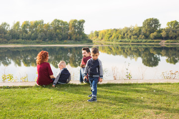 Children, parenthood and nature concept - Big family sitting on the grass