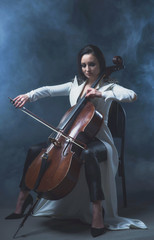Beautiful woman in a white coat plays the cello