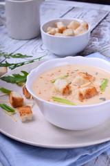 Cream soup with croutons, green onion and cheese in a white bowl
