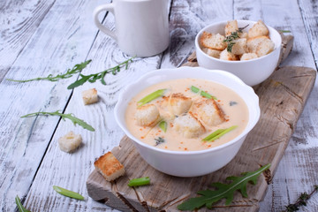 Cream soup with croutons, green onion and cheese in a white bowl