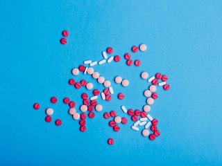 Multicolored medical pills and drugs on blue background