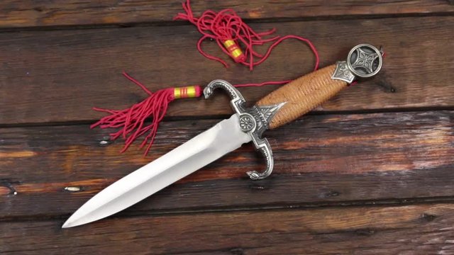 Crane camera , moving up, dagger lying on a beautiful, old wooden desk with copy space.